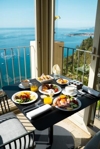 a table with plates of food on a balcony at Hotel Metropole Taormina in Taormina