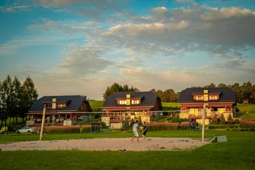 two people walking in front of a large house at AURA Centrum Wypoczynkowo-Rekreacyjne in Sejny