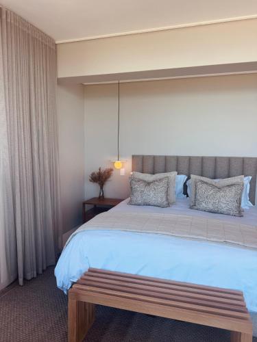 a bedroom with a large bed with a bench on it at Salt and Sand in Wilderness