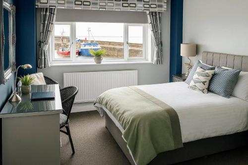 a bedroom with a bed and a desk and a window at Salt on the Harbour in Bridlington