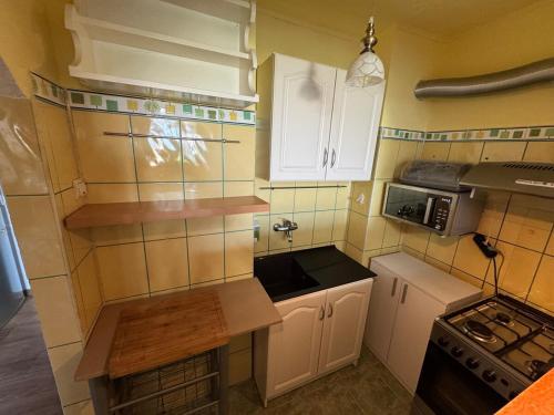 a small kitchen with white cabinets and a microwave at Small apartment in Hunedoara in Hunedoara