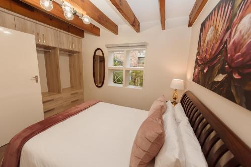 een slaapkamer met een bed en een schilderij aan de muur bij Protea Garden Cottage in Stellenbosch