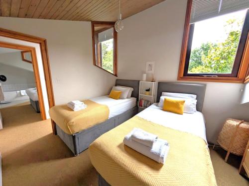 a room with two beds and two windows at Unique & Rural Child Friendly Annexe with Large Gardens, Games & Tennis Court - Chichester Holiday Properties in Chichester