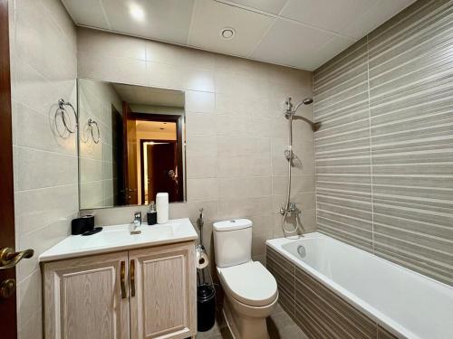 a bathroom with a toilet and a sink and a tub at Waterfront Modern loft overlooking downtown 3BR in Sharjah