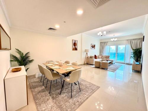 a dining room and living room with a table and chairs at Waterfront Modern loft overlooking downtown 3BR in Sharjah