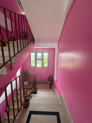 a hallway with pink walls and stairs with potted plants at Odyssey Stays Nongrim, Cherrapunji in Cherrapunji