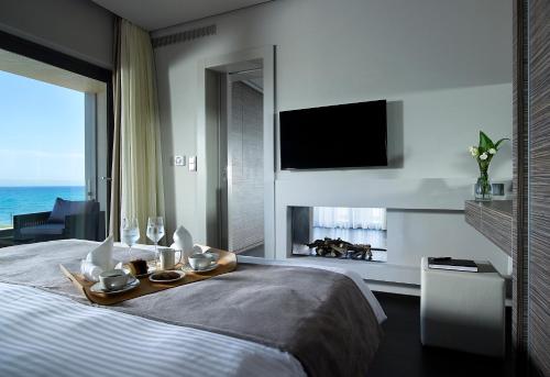 a bedroom with a bed with a fireplace and a television at NEMA Design Hotel & Spa - Adults Only in Hersonissos