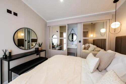 a bedroom with a large white bed and a mirror at Sunniva Lodge in Malton