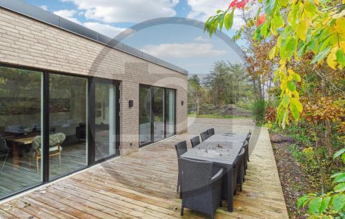 un patio con mesa y sillas en una terraza de madera en 4 Bedroom Awesome Home In Thyholm, en Oddesund Syd