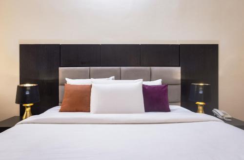 a bedroom with a large white bed with colorful pillows at ROYALE CROWN VILLA in Abuja