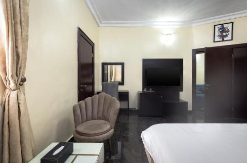 a hotel room with a bed and a chair and a television at ROYALE CROWN VILLA in Abuja