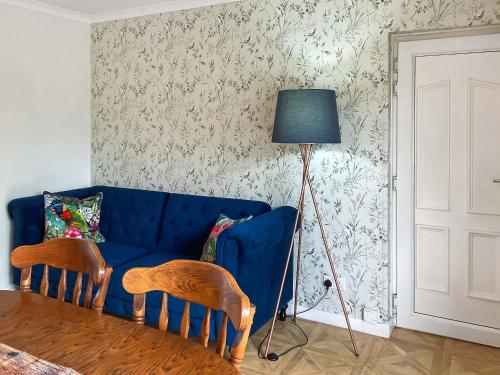 a living room with a blue couch and a lamp at The Room Next Door in Flemingston
