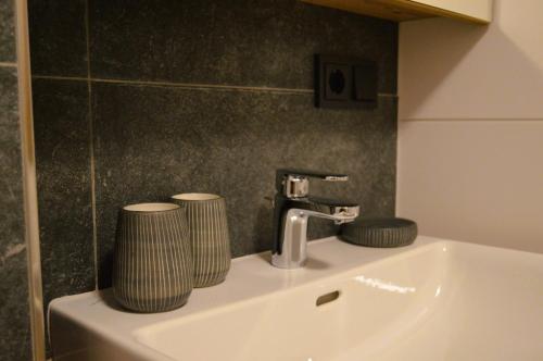 a bathroom sink with a faucet and two cups on it at Ferienwohnung Rohrmoser mit 2 Schlafzimmern in Hüttschlag