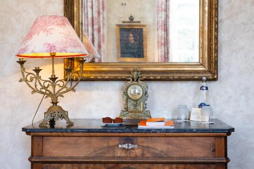 a lamp on a dresser with a clock and a mirror at Le Clair de la Plume - Teritoria in Grignan