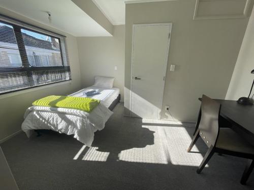 a bedroom with a bed and a desk and a window at Centre and Convenience Vacant Home in Pokeno