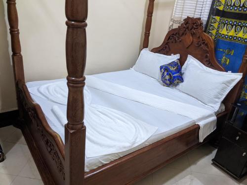 a bed with white sheets and pillows on it at Gs Villa Zanzibar in Zanzibar City