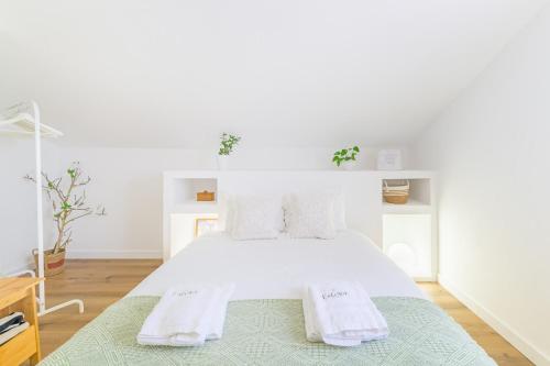 a white bedroom with a bed with towels on it at Esteva CountryHouse in Rogil