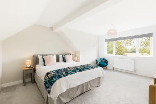 a white bedroom with a bed and a window at Pass the Keys Modern family home Garden Parking in Bourton on the Water