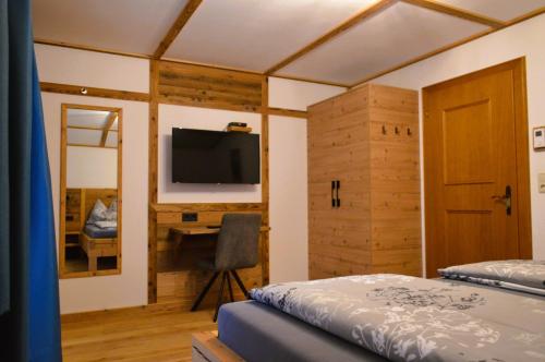 a bedroom with a bed and a desk and a television at Ferienwohnung Rohrmoser mit 1 Schlafzimmer in Hüttschlag