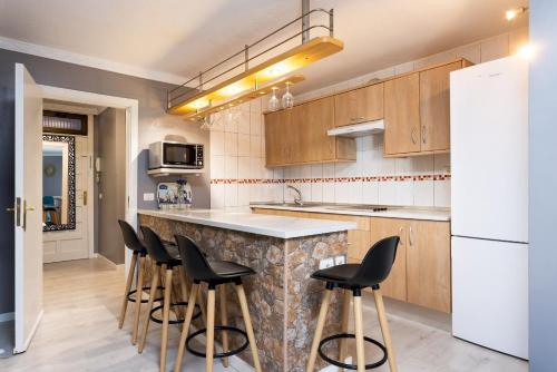 cocina con encimera de mármol y taburetes en Home2Book Relaxing Coastal Apt with Terrace, en Puerto de la Madera