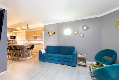Una sala de estar con un sofá azul y una cocina. en Home2Book Relaxing Coastal Apt with Terrace, en Puerto de la Madera