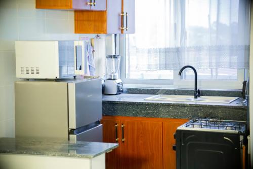 a kitchen with a stainless steel refrigerator and a sink at Toria Homes in Namulanda
