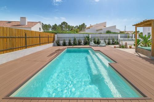 a swimming pool in a backyard with a wooden deck at Esteva CountryHouse in Rogil