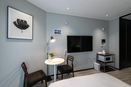 a room with a bed and a table and a tv at 모어댄 속초해변점 in Sokcho
