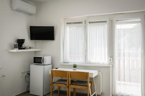 a kitchen with a table and two chairs and a refrigerator at Omni Residence Vendégház in Bük