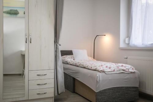 a small bedroom with a bed and a dresser at Omni Residence Vendégház in Bük