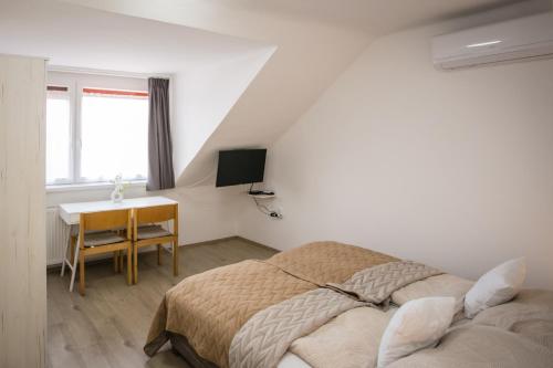 a bedroom with a bed and a desk at Omni Residence Vendégház in Bük
