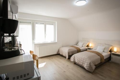 a white room with two beds and a couch at Omni Residence Vendégház in Bük
