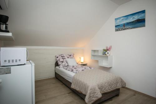 a small bedroom with a bed and a refrigerator at Omni Residence Vendégház in Bük