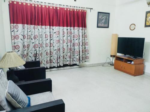 a living room with a couch and a television at Gulshan Elegant Center 3 BR AC Flat Near Cafes & Shops Heart of Gulshan in Dhaka