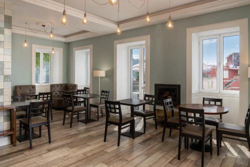 a dining room with tables and chairs and windows at OurMadeira - Babosas Village, gardénias and greenspaces in Funchal