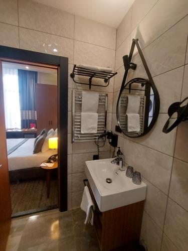 a bathroom with a sink and a mirror and a bed at Ramada by Wyndham Budapest City Center in Budapest