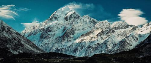 a snow covered mountain with a blue sky and clouds at Glentanner Park Centre in Glentanner