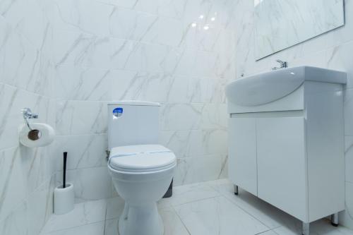 a white bathroom with a toilet and a sink at Seven Apart Hotel in Vyshneve