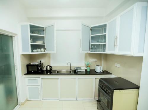 a white kitchen with white cabinets and a sink at K's Cove in Kandy