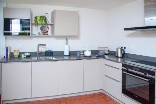 a kitchen with white cabinets and a sink at The Butler's Flat at Solsgirth Home Farm in Dollar
