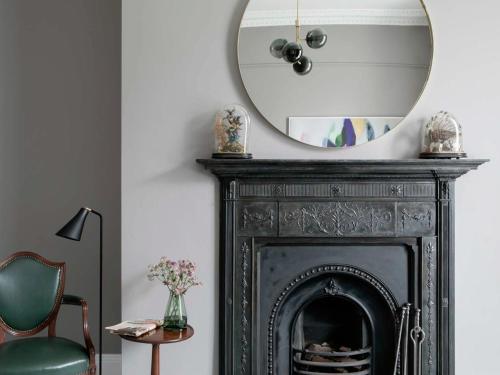 a mirror above a fireplace with a green chair at Pembroke Hall in Dublin