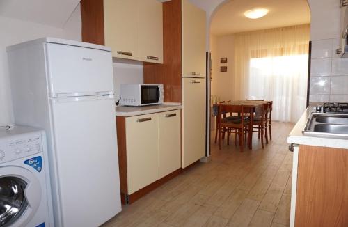 a kitchen with a white refrigerator and a table at Cozy villa with private garden-Beahost in Porto Santa Margherita di Caorle
