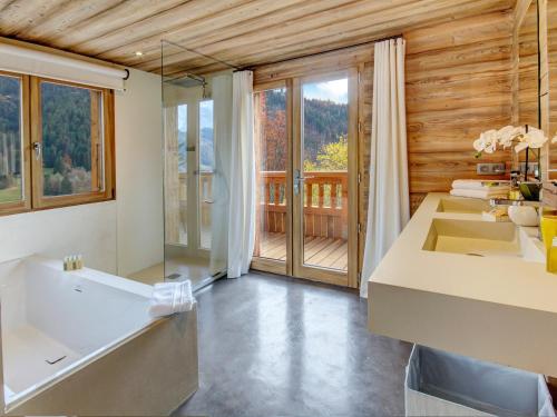 une salle de bain avec une grande baignoire et un balcon dans l'établissement Chalet 5★, 15 pers, 7 chambres, piscine, proche pistes à La Clusaz - FR-1-304-299, à La Clusaz
