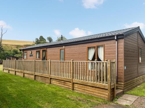 a wooden cabin with a fence in a yard at Glen View Lodge in Innerwick