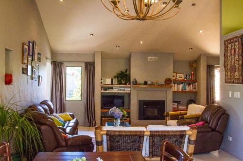 a living room with leather furniture and a chandelier at Taigh na Mara Bed and Breakfast in Whitianga