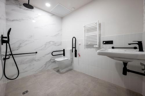 a white bathroom with a sink and a toilet at Pensión SÖMN Donostia in Donostia-San Sebastián