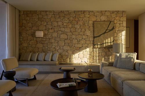 a living room with a couch and a stone wall at Mantri Villa, a Celestial Retreat with Endless Blue, By ThinkVilla in Neokhórion