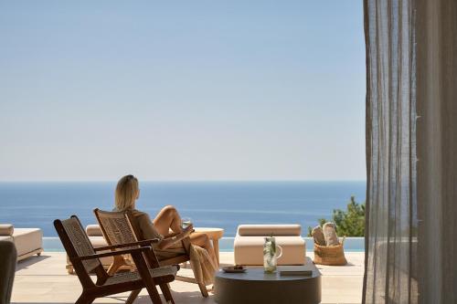 a woman sitting in a chair looking out at the ocean at Mantri Villa, a Celestial Retreat with Endless Blue, By ThinkVilla in Neokhórion