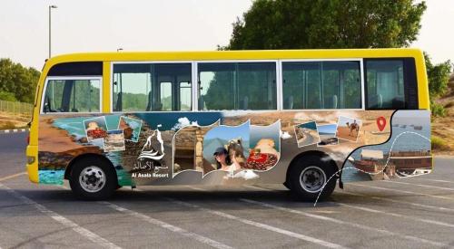 a yellow bus parked in a parking lot at أكواخ الأصاله 