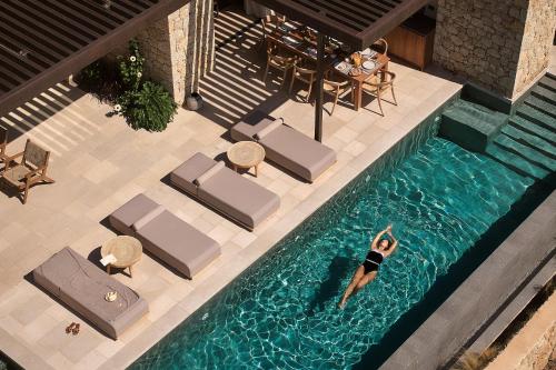 an overhead view of a woman swimming in a swimming pool at Mantri Villa, a Celestial Retreat with Endless Blue, By ThinkVilla in Neokhórion